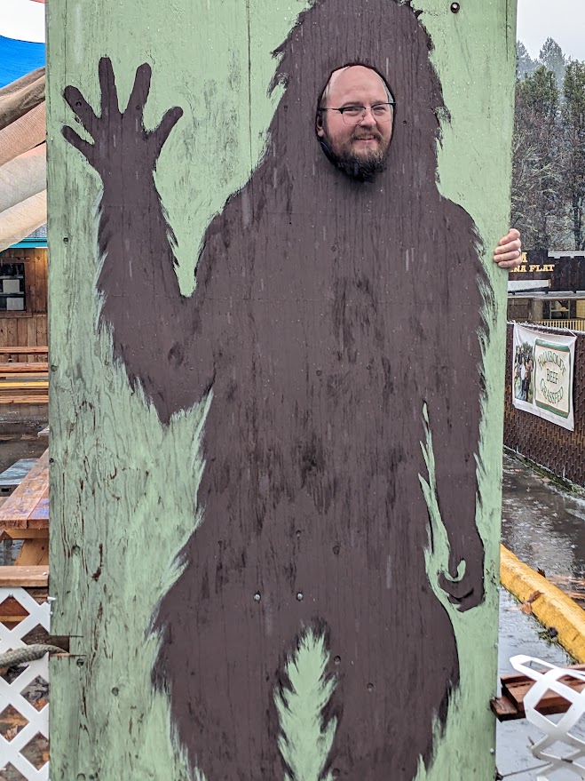 a man with his head in a wooden display that is a bigfoot body